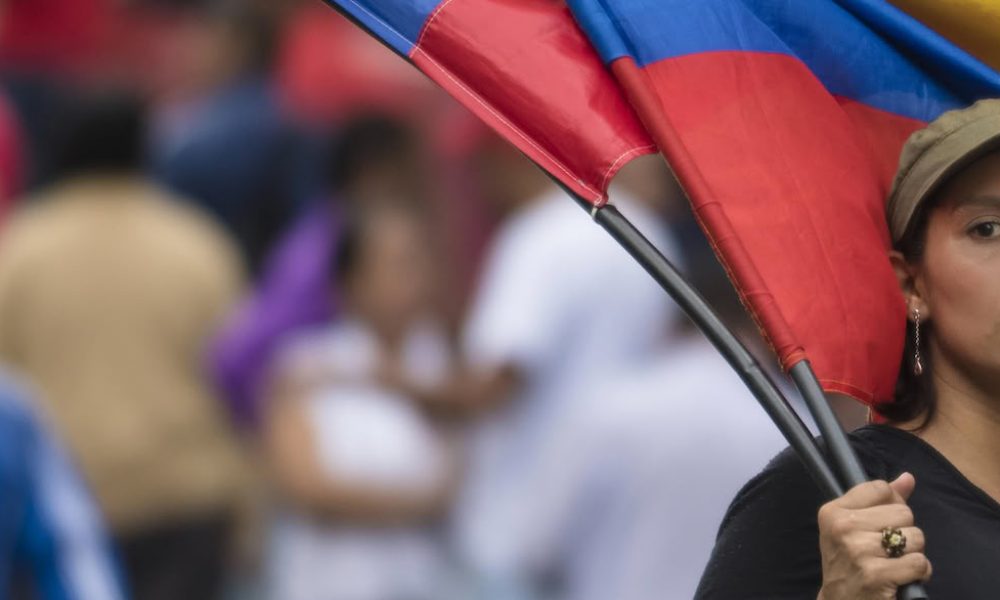 Mujer sosteniendo banderas venezolanas en manifestación callejera