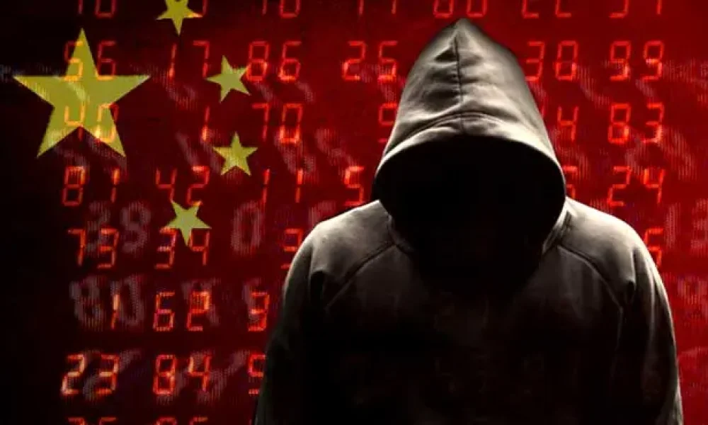 Figura encapuchada frente a código digital y bandera china, representando ciberespionaje