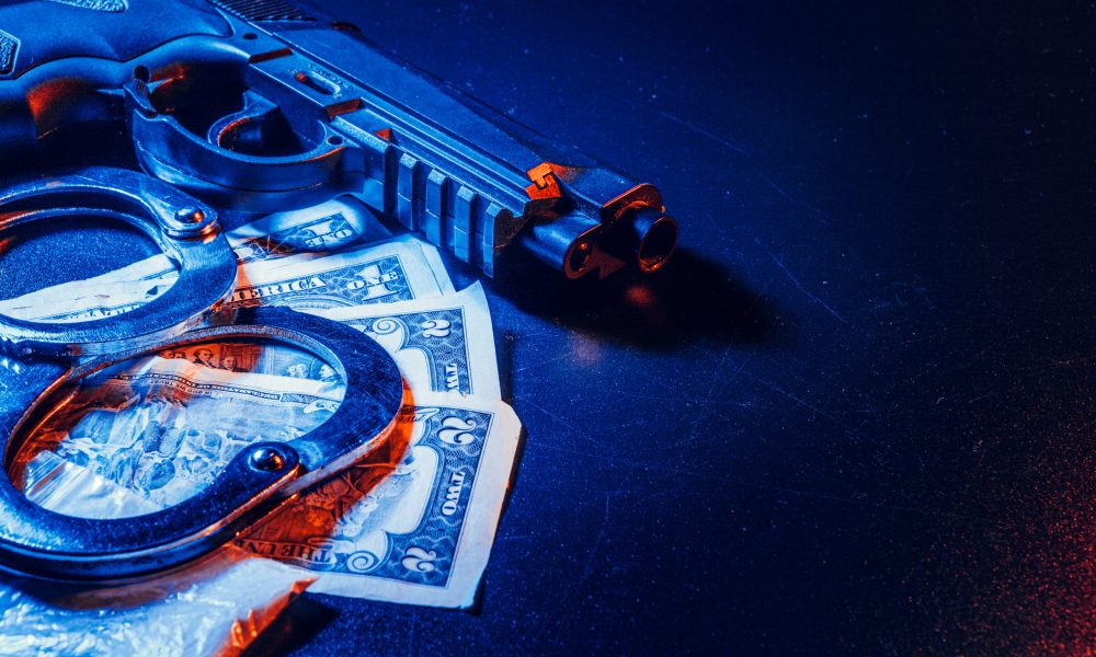 Arma de fuego, esposas y billetes de dlar sobre una mesa, representando crimen e inseguridad en Centroamrica